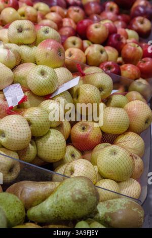 Riga, Latvia. August 30h 2023. Fresh pears and apples in red shopping net. Fruits arranged in the grocery store on the counter. Green pears, apples wi Stock Photo