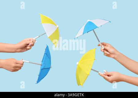 Female hands with different mini umbrellas on blue background Stock Photo