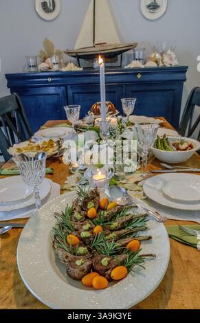 Easter dinner with lamb, deviled eggs, and carrot cake on porcelain dishs rimmed with gold on an Easter decorated table setting with lilies, butterfli Stock Photo