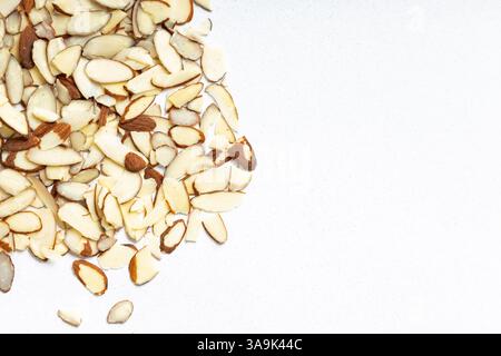 Sliced almonds scattered on a light surface in a kitchen setting, top view Stock Photo