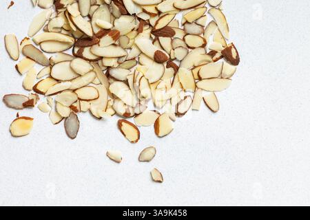 Sliced almonds scattered on a light surface in a kitchen setting, top view Stock Photo