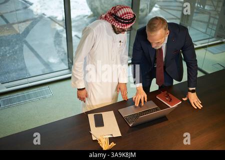 High angle view of two ethnically diverse male entrepreneurs working together on new business project, using laptop Stock Photo
