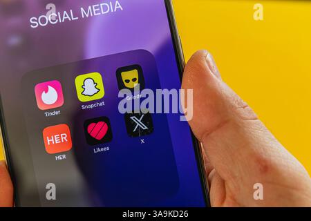 03.26.25 Lviv Ukraine A hand interacts with a smartphone displaying popular social media applications, including dating platforms, against a vibrant y Stock Photo