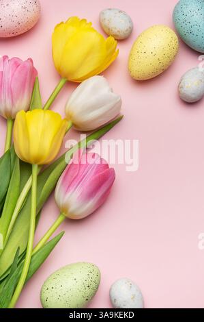 Easter eggs and tulips arranged on a pink background creating a vibrant spring border with copy space Stock Photo