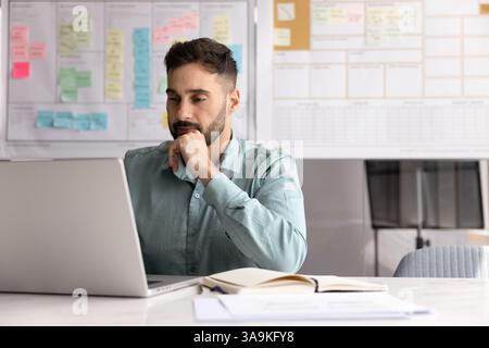 Focused Latin project manager man working at computer Stock Photo