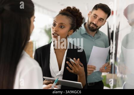 Young African businesswoman talking to colleagues, meeting with coworkers Stock Photo