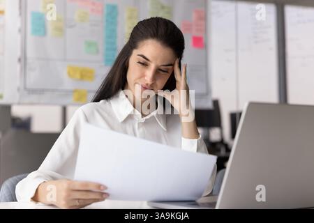 Thoughtful concerned Latin business professional woman reading financial document Stock Photo