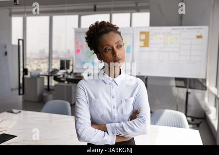 Serious African American businesswoman standing with hands crossed in office Stock Photo
