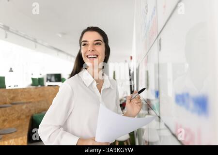 Cheerful Hispanic business leader woman writing on white scrum board Stock Photo