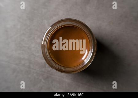 Top view of chocolate spread or nougat cream with hazelnuts in glass jar on dark background Stock Photo