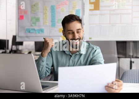 Excited positive Hispanic businessman reading paper letter with good news Stock Photo