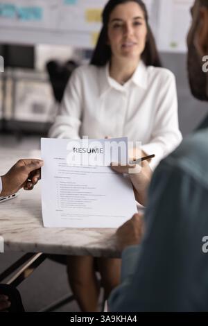 Two recruit managers holding paper resume, talking to job candidate Stock Photo