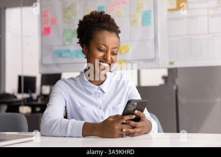 Happy positive African American business woman using mobile phone Stock Photo