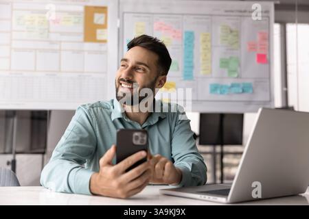 Happy project manager man using mobile phone at office workplace Stock Photo