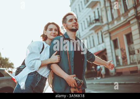 Young happy stylish couple of lovers catch a car in the city. Hitchhiking concept Stock Photo