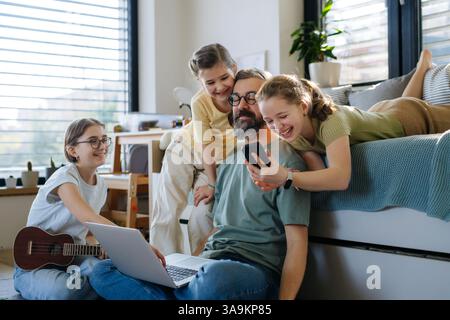 Father with three daughters trying to work from homeoffice. Stock Photo