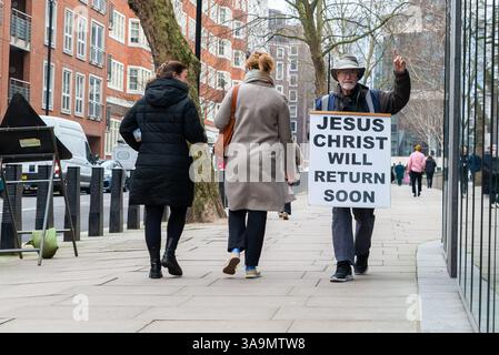 Jesus Christ will return soon, on a sandwich board of a senior white Caucasian male walking the street in Westminster, London, UK. Second coming Stock Photo