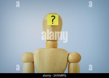 Wooden mannequin with sticky note on forehead with question mark Stock Photo