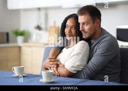Interracial couple looking away together in the kitchen at home Stock Photo