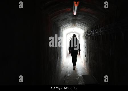 27 March 2025, Schleswig-Holstein, Helgoland: A participant walks through the Weddigenstollen tunnel during a guided tour of the civil defense bunker on the Oberland of the offshore island of Heligoland. On April 18 and 19, 1945, British bombers flew countless raids against military installations on Heligoland. Around 2,600 Heligoland residents survived the bombing raids in the civil defense bunker. The air raids made the island uninhabitable and the British took control of the North Sea island. In 1947, the British also blew up all military installations with 6,700 tons of ammunition in the s Stock Photo