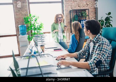 Three colleagues communicate and collaborate in a bright modern office with natural light, fostering teamwork Stock Photo