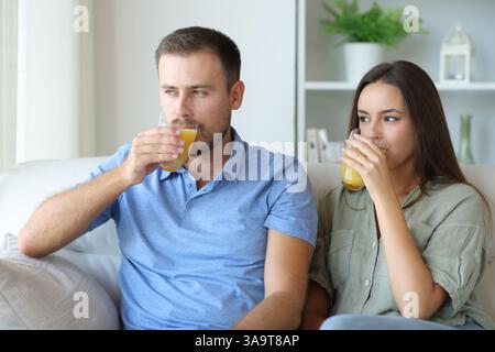Couple drinking orange juice sitting on a couch at home Stock Photo