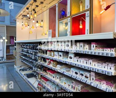 Paris, France - Mar 27, 2025: Pendant bulbs in various designs and colorful enclosures hang above a well-stocked aisle of lighting accessories and box Stock Photo
