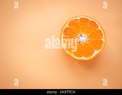 Overhead view of clementine cut in half on orange background. Stock Photo