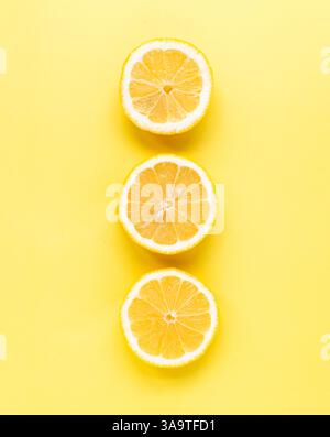 Overhead view of three slices of lemon on yellow background. Stock Photo