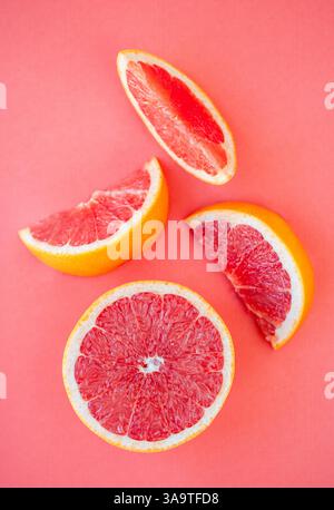 Overhead close up of grapefruit half and segments on pink background. Stock Photo