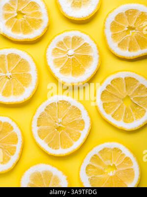 Overhead close up of many lemon slices on yellow background. Stock Photo