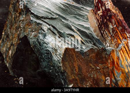Big stone with rough corners in stone ZEN garden. A grey brown rock with sharp edges and textured surface on a racked black sand. Natural stones rocks Stock Photo