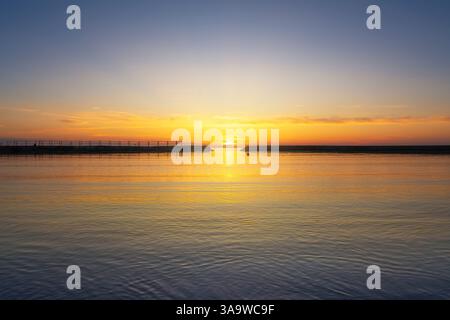 The sun setting over the sea in the middle of the breakwater entrance. Lillatro, Rosignano Solvay, province of Livorno, Tuscany, Italy Stock Photo