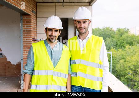 Engineers wearing safety vests and helmets supervising construction site Stock Photo