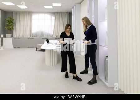 Team members collaborate in modern office space while discussing project details and reviewing documents together Stock Photo