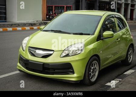 Front view of a 4 door mini car green color parked on a street. Modern compact car parked outdoors in urban city. Close up view of a hatchback car. No Stock Photo
