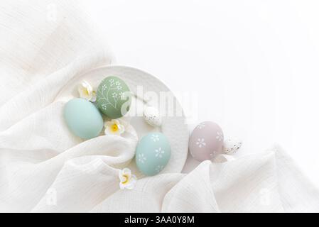 Stylish easter eggs and spring flowers on linen cloth on white table. Happy Easter concept. Top view Stock Photo