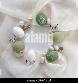 Frame from decorated Easter eggs, green pastel colors and linen cloth on white table. Flat lay, round frame, top view Stock Photo