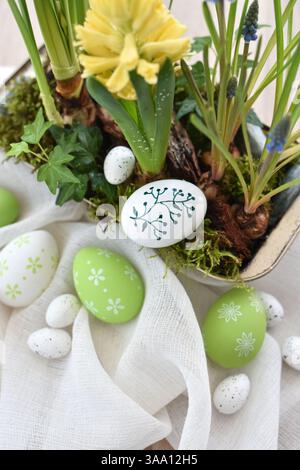 Stylish decorated easter eggs on linen cloth and spring primroses in a pot. Easter still life Stock Photo