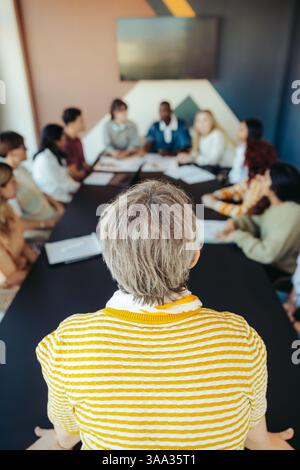 A group of students engages in a lively discussion, seated around a table in a contemporary academic setting promoting collaborative learning. Stock Photo