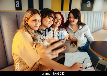 A cheerful group of friends taking a selfie together in a classroom setting, showcasing friendship, fun, and student life experiences. Stock Photo