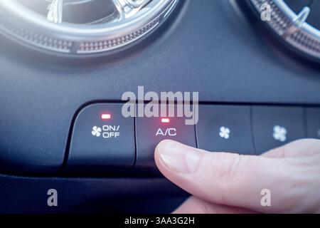 A hand skillfully adjusting the air conditioning button located in a cars climate control system for comfort Stock Photo
