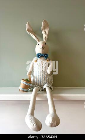 Cute stuffed Easter bunny holding a basket filled with colorful eggs. Stock Photo