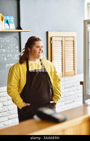 A young woman with Down syndrome confidently poses in a cafe, wearing casual attire. Stock Photo