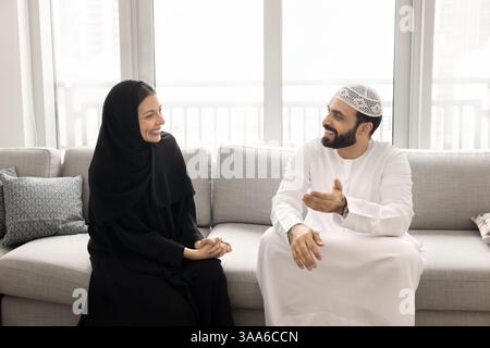 Happy couple sit on sofa, engaged in pleasant conversation Stock Photo