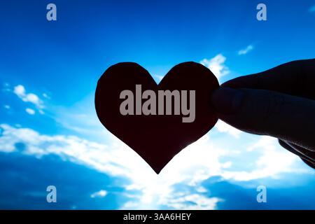 Heart Shape in the Hand on the Sky Background Stock Photo