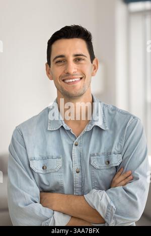 Handsome man in casual blue shirt posing indoor with arms-crossed Stock Photo