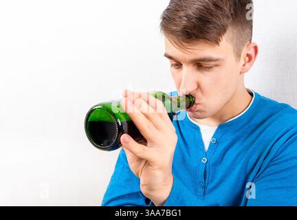 Young Man drink a Beer by the Wall in the Room closeup Stock Photo
