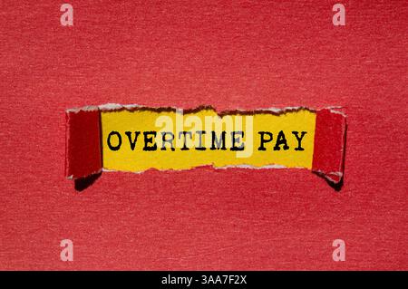 Overtime pay message written on ripped torn red paper on yellow background. Conceptual overtime pay symbol. Copy space. Stock Photo