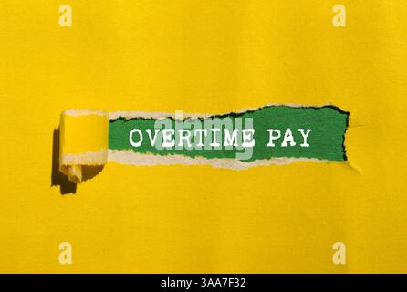 Overtime pay message written on ripped torn yellow paper on green background. Conceptual overtime pay symbol. Copy space. Stock Photo